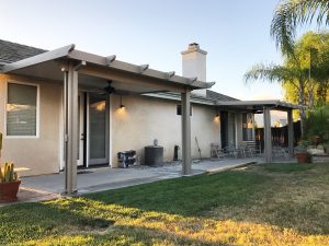 Two small patio covers installed in separate sections of a backyard patio