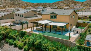 Two-story earth-tone house with a large patio cover covering the width of the house